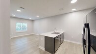 Located at 2430 W Kilgore Ave in Muncie, Indiana, this well-appointed one-bedroom, one-bathroom unit offers a thoughtfully designed single-floor layout with modern finishes throughout. Light-wood luxury vinyl flooring flows seamlessly across every room, complemented by neutral gray walls and crisp white trim.

The open-concept kitchen and living area serves as the heart of the unit. The kitchen features bold gray shaker-style cabinetry, white countertops with a peninsula island and integrated sink, and a full suite of black appliances including a refrigerator with ice maker, electric range, and over-the-range microwave. Recessed lighting illuminates the space, creating a clean and functional environment.

The bedroom is a comfortable, well-proportioned room with recessed lighting, a large window offering views of lush greenery, and access to a dedicated walk-in closet outfitted with wire shelving for organized storage.

The bathroom continues the cohesive design with wood-look tile flooring, dark cabinetry with a vanity, and a clean, efficient layout. Throughout the unit, large windows with blinds invite natural light while maintaining privacy, and the neutral color palette creates a bright, move-in-ready atmosphere ideal for modern living.