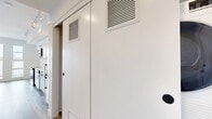 Located at 3949 Shelbourne St in Saanich, BC, this thoughtfully designed single-floor studio offers a compact yet functional layout comprising an entrance, kitchen, bathroom, and open living area. The interior showcases a clean, contemporary aesthetic with light hardwood-style flooring running throughout the main living space, crisp white walls, and an abundance of natural light streaming in through large floor-to-ceiling windows that open to an outdoor balcony view.

The kitchen is a standout feature, finished with full-height white cabinetry equipped with matte black hardware, white quartz countertops, and a classic white subway tile backsplash laid in a horizontal stacked pattern. Stainless steel appliances — including a range, built-in microwave, dishwasher, and refrigerator — provide a modern, functional cooking space. Track lighting overhead adds both practicality and style.

The bathroom continues the modern white theme, featuring a white quartz vanity countertop with an undermount sink, light wood cabinetry with matte black hardware, large mirror, and clean tile flooring. Space-saving sliding doors are incorporated into the layout, enhancing flow and efficiency. HVAC vents are thoughtfully integrated into the walls, ensuring year-round comfort throughout this well-appointed Saanich residence.