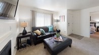 This 1-bedroom, 1-bathroom unit is designed for practical, comfortable living across a single floor. The living room serves as the central gathering space, featuring a fireplace, a large window with vertical blinds that allows natural light to fill the room, and neutral carpet flooring. The adjacent dining area benefits from its own window overlooking the outdoors and is outfitted with a ceiling fan, blue accent wall, and ample space for a full dining set.

The galley-style kitchen is efficiently arranged with warm wood-toned cabinetry, white appliances including a refrigerator, range, and microwave, and wood-look flooring that extends throughout the space. A door in the kitchen provides additional access, adding convenience to the layout.

The bedroom is a calm, carpeted retreat with a window offering outdoor views and sufficient space for a full furniture arrangement. The full bathroom features a wood-look tile floor, warm oak cabinetry with a single vanity, a large mirror, and a tub/shower combination. The overall design is clean and neutral, providing a functional and welcoming living environment.