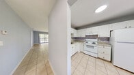 Located at 4789 Lake Arjaro Dr in West Palm Beach, Florida, this two-bedroom, two-bathroom single-floor residence offers a practical and well-organized floor plan. Light beige ceramic tile flooring flows consistently throughout the home, complementing the soft gray-blue painted walls and white trim for a clean, neutral aesthetic.

A hallway entrance leads into the heart of the home, connecting the kitchen to the open combined dining and living area. The kitchen features white cabinetry, granite-style countertops, a decorative tile backsplash, and white appliances including a range, dishwasher, and a pass-through window that opens to the living area—an ideal detail for entertaining. The spacious combined living and dining room receives natural light through a large sliding glass door that opens to the balcony.

Both bedrooms are comfortably sized, each with windows offering views of surrounding greenery and access to dedicated closets. The primary bedroom includes its own en-suite bathroom featuring a walk-in shower with wood-look tile walls and a classic penny tile floor. The second bathroom offers a full soaking tub with large-format travertine-style tile surround. The home also includes a hallway for added layout efficiency and privacy between rooms.