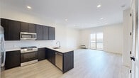 Located at 487 Market St in Saddle Brook, NJ, this modern one-bedroom, one-bathroom residence offers a thoughtfully designed open-concept layout across a single floor. Light wood-tone flooring flows throughout, complementing the bright white walls and recessed lighting that give the space a clean, contemporary feel.

The combined kitchen and living area forms the heart of the unit. The kitchen is outfitted with dark espresso cabinetry, a white quartz peninsula countertop, a stainless steel appliance suite including a gas range, built-in microwave, and French door refrigerator, along with a subway tile backsplash. The open living area receives natural light through a sliding glass door that leads to an outdoor balcony.

The spacious primary bedroom also benefits from natural light via a large window with outdoor views, and includes a well-organized walk-in closet with built-in shelving and hanging rods. An additional closet provides further storage. A versatile den offers flexible space for a home office or additional living area.

The bathroom features neutral tile flooring and walls, a floating wood-toned vanity with a round mirror, and a walk-in shower. In-unit laundry adds everyday convenience, completing this well-appointed and efficiently designed residence.