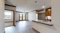 This thoughtfully designed single-floor residence offers a seamless open-concept layout that connects the living area and kitchen, creating a spacious and functional living environment. The kitchen is a standout feature, showcasing warm wood cabinetry, granite countertops, stainless steel appliances, and a central island with a built-in sink and pendant lighting overhead. The living area extends naturally from the kitchen, highlighted by crown molding, a ceiling fan, and French doors that invite natural light and provide outdoor views. A built-in mudroom with shelving, hooks, and a bench adds a practical organizational element near the entryway. The primary bedroom is generously sized with hardwood-style flooring, crown molding, a ceiling fan, and direct access to a private en suite bathroom. The en suite features a granite-topped vanity and a walk-in closet. Additional bedrooms are carpeted, each with ceiling fans and windows offering natural light. The secondary bathroom includes a granite vanity, a tub-shower combination with tile surround, and hardwood-style flooring. Throughout the residence, consistent finishes including neutral tones, wood-look flooring, and dark trim create a cohesive and modern aesthetic.