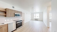 This well-designed 2-bedroom, 2-bathroom apartment at 1145 SW 170th Ave in Beaverton, Oregon offers a clean, modern aesthetic throughout its thoughtfully laid-out single-floor plan. Light wood-tone flooring flows consistently across all living areas, complementing the bright white walls and creating a warm, cohesive atmosphere.

The open kitchen and living area serves as the heart of the home. The kitchen is outfitted with a full suite of stainless steel appliances, including a French door refrigerator, electric range, built-in microwave, and dishwasher. Warm wood-grain cabinetry, light countertops, and a subway tile backsplash complete the contemporary look.

The living area is spacious and open, with a floor vent and clean sightlines leading toward the entry. Both bedrooms are comfortably sized, with the primary bedroom offering generous dimensions. Each bedroom features large windows that bring in natural light and provide views of the surrounding neighborhood, along with built-in closet bars for storage.

The two bathrooms each feature a full tub-shower combination with chrome fixtures and white surrounds. One bathroom conveniently includes a stacked washer and dryer unit, adding practical in-unit laundry access. A dedicated closet provides additional storage within the unit.