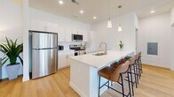 Located in Cedar City, Utah, this single-story, 2-bedroom, 2-bathroom home offers a thoughtfully designed interior with a clean, modern aesthetic. The open-concept kitchen and living area serves as the heart of the home, featuring warm light wood flooring, white flat-panel cabinetry, stainless steel appliances, and a spacious island with bar seating and pendant lighting — ideal for both cooking and casual dining. The living room flows naturally from the kitchen, with large windows that invite abundant natural light, white walls, and hardwood-style flooring that lends a bright, airy feel throughout. The primary bedroom is a comfortable retreat with plush carpet, a ceiling fan, and windows with sheer curtains. It connects to a well-appointed en-suite bathroom with a double vanity, white cabinetry, and a walk-in shower. The second bedroom is bright and inviting, also featuring carpet flooring and a large window. A second full bathroom includes a soaking tub, white vanity, and light wood flooring. Three closets provide generous storage throughout the home. The consistent palette of whites and warm wood tones creates a cohesive, contemporary ambiance suited to comfortable everyday living.