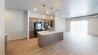 Located at 5501 E 18th St in Sioux Falls, South Dakota, this single-floor unit offers a well-designed, open layout with contemporary finishes throughout. The kitchen serves as a central highlight, featuring rich dark cabinetry, light stone countertops, a center island with a built-in sink, pendant lighting, and black appliances. It opens seamlessly into the living area, which benefits from natural light through a sliding glass door. The flooring throughout the main living areas and kitchen is a warm-toned luxury vinyl plank, while carpeting adds comfort to the bedrooms. The bedrooms are generously sized, with one featuring dual windows that allow abundant natural light and exposed ductwork that adds an industrial touch. Storage is well-addressed with multiple closets, including a walk-in closet with wire shelving and a secondary reach-in closet. Two bathrooms serve the unit — one with a tub/shower combo and dark wood vanity, and another with stylish gold-toned vanity lighting and a single-sink vanity with matching cabinetry. A dedicated in-unit laundry room includes a full-size front-loading washer and dryer with additional wire shelving. The unit presents a clean, neutral palette with light gray walls and white trim throughout.