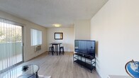 Located on North Orange Drive in the heart of Hollywood, Los Angeles, this single-floor unit offers a functional and well-organized layout. The living area serves as the central gathering space, featuring light wood-style flooring, a textured ceiling, and neutral wall tones that create a clean, understated aesthetic. A large sliding glass door and adjacent window allow natural light to flow in while offering views of the surrounding greenery. A wall-mounted air conditioning unit provides climate control, and there is ample space for a seating arrangement, television setup, and a compact workspace with a desk area.

The dining area is defined by its own dedicated corner, accommodating a bistro-style table and stools beneath flush ceiling lighting, with a wall mirror adding depth to the space. The kitchen is efficiently designed with white cabinetry, dark countertops, stainless steel appliances including a refrigerator, electric range, and built-in microwave, and light tile flooring. The bathroom features a combination shower and bathtub enclosed by sliding glass doors, white tile flooring, and clean white walls, providing a simple and practical layout. Together, these spaces form a compact yet cohesive single-floor unit in a prime Los Angeles location.