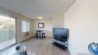 Located on North Orange Drive in the heart of Hollywood, Los Angeles, this single-floor unit offers a functional and well-organized layout. The living area serves as the central gathering space, featuring light wood-style flooring, a textured ceiling, and neutral wall tones that create a clean, understated aesthetic. A large sliding glass door and adjacent window allow natural light to flow in while offering views of the surrounding greenery. A wall-mounted air conditioning unit provides climate control, and there is ample space for a seating arrangement, television setup, and a compact workspace with a desk area.

The dining area is defined by its own dedicated corner, accommodating a bistro-style table and stools beneath flush ceiling lighting, with a wall mirror adding depth to the space. The kitchen is efficiently designed with white cabinetry, dark countertops, stainless steel appliances including a refrigerator, electric range, and built-in microwave, and light tile flooring. The bathroom features a combination shower and bathtub enclosed by sliding glass doors, white tile flooring, and clean white walls, providing a simple and practical layout. Together, these spaces form a compact yet cohesive single-floor unit in a prime Los Angeles location.