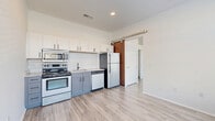 Located at 815 Kinnear Rd. in Columbus, Ohio, this one-bedroom, one-bathroom unit offers a thoughtfully designed layout with modern finishes throughout. Light wood-style flooring runs continuously across the entire space, lending a clean, cohesive aesthetic from room to room. Large windows in both the living area and bedroom allow abundant natural light to fill the interior, creating an open and airy atmosphere despite the unit's compact footprint. The open-concept living and kitchen area serves as the heart of the unit. The kitchen is well-appointed with two-tone cabinetry—white upper cabinets paired with slate-blue lower cabinets—complemented by a geometric honeycomb tile backsplash, granite-style countertops, and a full suite of stainless steel appliances including a range, microwave, dishwasher, and refrigerator. A distinctive sliding barn door adds a stylish architectural accent, separating the living space from the bedroom corridor. The bedroom is a comfortable, well-lit room with a large window overlooking the exterior. The bathroom features wood-style flooring, a granite-top vanity with white cabinetry, and a full tub-shower combination. A dedicated closet provides practical storage, completing this efficiently arranged urban residence.