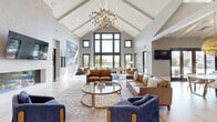 Located at 8201 Quivira Rd in Lenexa, Kansas, this thoughtfully designed single-floor communal space offers a sophisticated blend of modern aesthetics and functional design. The open-concept kitchen and living area serves as the heart of the space, showcasing soaring vaulted ceilings with exposed beams and a striking modern chandelier. The gourmet kitchen features custom flat-panel cabinetry in warm wood tones, quartz countertops, a large center island, stainless steel appliances, and a mosaic tile backsplash. Floor-to-ceiling glass doors flood the space with natural light and provide direct views of an outdoor pool area. Large-format tile flooring grounds the kitchen and dining area, which is anchored by a generously sized white dining table.

The living room impresses with its dramatic cathedral ceiling, an elegant linear gas fireplace set against a marble surround, and an expansive wall of windows that frame outdoor views. A sculptural chandelier adds a refined focal point overhead. A secondary lounge area offers a cozier atmosphere, complete with a coffered ceiling featuring decorative tin tile detailing, another linear fireplace, built-in workstations, and vibrant accent décor — making it ideal as a business center or quiet retreat.