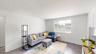 Located at 2343 Memorial Ave SW in Roanoke, Virginia, this single-floor, 2-bedroom, 1-bathroom home offers a clean, modern aesthetic with a light and airy feel throughout. The living room is a welcoming space, featuring neutral gray walls, hard-surface flooring, and a large window that fills the room with natural light and views of the surrounding greenery. A hallway connects the main living areas to the private quarters with ease. The dedicated dining room comfortably accommodates a full dining set and is brightened by its own window, creating a pleasant space for meals. The kitchen is thoughtfully appointed with crisp white cabinetry, light marble-style countertops, a stainless steel sink, dishwasher, and a full-size refrigerator. The spacious primary bedroom offers generous room for furnishings, while the second bedroom is cozy and well-lit with a window overlooking the exterior. Both rooms benefit from ample closet storage, with three closets distributed throughout the home. The full bathroom features a shower/tub combination, a window for natural ventilation, and a classic white vanity. Consistent hard-surface flooring runs throughout, tying the home together with a cohesive, contemporary style.