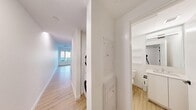This 1-bedroom, 1-bathroom unit in Calgary, AB offers a thoughtfully designed layout with a clean, modern aesthetic throughout. Light hardwood-style flooring runs continuously across all areas, complementing the crisp white walls and creating a bright, cohesive feel.

The kitchen is well-appointed with stainless steel appliances — including a refrigerator, electric range, built-in microwave, and dishwasher — paired with sleek white cabinetry that extends to the ceiling for ample storage. A large window and a private balcony door flood the space with natural light and provide easy outdoor access. A distinctive black-framed glass partition adds an architectural detail that visually connects the kitchen to the adjoining living area.

The bedroom is a quiet, light-filled space with a window and clean walls ready for personalization. The hallway efficiently connects all areas and features a stacked in-suite washer and dryer, a practical and convenient addition.

The bathroom is finished in a clean white palette, featuring a glass-enclosed walk-in shower with white tile surround, a toilet, a vanity with storage, and built-in open shelving for additional organization.

Overall, the unit presents a modern, functional, and well-lit living environment suited for comfortable urban living in Calgary.