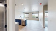 Located at 1 Main St in Menasha, WI, this thoughtfully designed one-bedroom, one-bathroom unit offers a efficient and modern living experience across a single floor. The open-concept living and kitchen area is anchored by a striking navy blue island with a white quartz countertop, undermount sink, and pendant lighting. Light wood-tone cabinetry lines the kitchen walls, complemented by a full suite of stainless steel appliances including a refrigerator with ice maker, electric range, over-the-range microwave, and dishwasher. Light wood-look plank flooring flows throughout the main living areas, while large black-framed windows allow natural light to fill the space and provide views of the surrounding neighborhood. The bedroom features plush carpeting, a black-framed window, and a spacious walk-in closet outfitted with wire shelving for ample storage. The full bathroom is finished with a light wood vanity, white quartz countertop, soaking tub with shower surround, and matching light flooring. A dedicated laundry area houses a stacked washer and dryer unit alongside additional closet shelving. The neutral color palette and clean-lined design create a contemporary, move-in-ready atmosphere throughout.