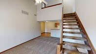 Located at 372 James Way in Marion, Ohio, this two-story, two-bedroom, two-bathroom home offers a well-organized layout spread across two floors. The main level immediately impresses with dramatic vaulted ceilings and an open living area anchored by a ceiling fan, creating an airy and spacious atmosphere. A carpeted living room flows toward the kitchen, which features warm oak cabinetry, white appliances including a gas range and refrigerator, a double sink, and wood-look flooring that extends through the dining area. The open pass-through design connects the kitchen seamlessly to the surrounding living spaces. A staircase with a classic wood banister leads to the upper level, where the two bedrooms are located. The primary bedroom offers a comfortable footprint with carpeted flooring and natural light from a window, accompanied by a walk-in closet outfitted with wire shelving for generous storage. The secondary bedroom is similarly carpeted and well-lit. Both bathrooms are identically appointed with a tub-shower combination, single-sink vanity, and wood-look tile flooring. Three hallways provide logical circulation throughout the home, and two closets add additional storage. The neutral color palette and consistent finishes throughout lend the home a clean, functional character.