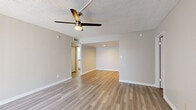 This single-story, 3-bedroom, 2-bathroom residence offers a thoughtfully designed layout with consistent wood-look laminate flooring running throughout every room. The open living area is a welcoming centerpiece, featuring a textured ceiling, a ceiling fan with light fixture, and a sliding glass door fitted with vertical blinds that fills the space with natural light and provides access to the outdoors. An additional connected area extends the living space further, offering flexibility for dining or lounging.

The galley-style kitchen is efficiently organized with white shaker cabinetry, grey countertops, white subway tile backsplash, and a full suite of stainless steel appliances including a refrigerator, electric range, and over-the-range microwave.

Each of the three bedrooms features a ceiling fan, wood-look flooring, and windows with horizontal blinds for natural light and privacy. The primary bedroom is a comfortable size and connects to its own dedicated space within the layout.

Both bathrooms are finished with white vanity cabinetry, grey countertops, undermount sinks, and framed mirrors. One bathroom includes a full tub-shower combination and conveniently accommodates a stacked washer and dryer unit. A hallway, closet, and dedicated entrance complete the functional floor plan.