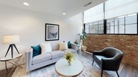 This two-floor space masterfully combines industrial heritage with contemporary design. Exposed brick walls are a defining architectural feature throughout, lending warmth and character to multiple rooms, including the bedrooms and a uniquely appointed bathroom. The living area is an inviting, open space anchored by dark hardwood flooring, large steel-framed windows that draw in natural light, and a split-level layout that adds visual depth and dimension.

The kitchen is outfitted with modern light wood cabinetry, dark granite countertops, a subway tile backsplash, and stainless steel appliances, offering both style and functionality. Adjacent to the kitchen, the dining area accommodates generous seating around a solid wood farmhouse-style table, complemented by bar seating along a wall-mounted counter.

The bedrooms feature exposed brick accent walls that soar upward, creating a dramatic, loft-like atmosphere. The bathrooms are clean and contemporary, finished with wood-toned vanities, white countertops, and tile flooring. One bathroom showcases raw brick walls for a distinctive, artistic touch.

Throughout the space, recessed lighting, curated wall art, and thoughtful décor tie together the industrial and modern aesthetic into a cohesive, well-appointed environment.