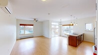 Located at 237 North Ave, Unit 24 in Burlington, Vermont, this three-bedroom, two-bathroom unit offers a well-designed single-level layout with a functional and comfortable floor plan. The open-concept living and kitchen area serves as the heart of the home, bathed in natural light from multiple large windows and a sliding glass door that leads to a private balcony with neighborhood views. Light-toned hardwood-style flooring runs throughout the main living areas, complementing the bright, neutral walls and adding a clean, modern feel. The kitchen is well-appointed with rich cherry-toned cabinetry, stainless steel appliances including a range, microwave, and refrigerator, a double-basin sink set into a peninsula with pendant lighting above — ideal for casual dining or entertaining. The living room features a ceiling fan and ample space for varied furniture arrangements. Each of the three bedrooms is carpeted for comfort and includes its own ceiling fan and window for natural light and ventilation. The spacious primary bedroom offers generous room for a full bedroom suite. Two full bathrooms serve the unit, including one with a walk-in shower, tile flooring, and dark wood vanity cabinetry. A central hallway connects the bedrooms and includes open closet storage, rounding out this thoughtfully laid-out Burlington home.