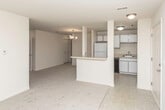 Located at 2871 Scenic Ct in Lake Orion, Michigan, this single-floor unit offers a practical and comfortable layout designed for everyday living. The living area is generously sized, featuring neutral-toned carpet, cream-colored walls, and a large sliding glass door fitted with vertical blinds that provides access to an outdoor area while drawing in natural light and views of the surrounding neighborhood.

The kitchen is positioned in an open-concept arrangement, separated from the living space by a half-wall breakfast bar with a pendant light fixture overhead. White cabinetry, laminate countertops in an L-shaped configuration, a stainless steel sink, and white appliances including a range and refrigerator define the kitchen's functional design. Tile flooring runs throughout this area.

Multiple carpeted rooms branch off a central hallway, each offering natural light through windows dressed with vertical blinds. One room includes access to a walk-in closet area, providing useful storage. The unit includes two bathrooms: one featuring wood-look tile flooring, a vanity, and a glass-enclosed shower stall, and a second with a full tub-shower combination and similar wood-look flooring. The overall palette throughout is light and neutral, contributing to a clean and airy atmosphere.