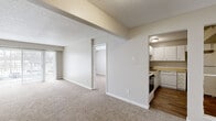 This single-floor residential unit offers a practical and well-organized layout designed for comfortable everyday living. The open living area is finished with plush wall-to-wall carpeting and neutral tones, creating a bright and welcoming atmosphere. A sliding glass door provides access to an outdoor balcony or patio, allowing natural light to fill the space. A textured ceiling and clean white trim add a classic touch throughout.

The kitchen is efficiently designed with white cabinetry, laminate countertops, and wood-style flooring. It is equipped with a full suite of white appliances, including a refrigerator, dishwasher, and electric range, along with ample cabinet storage and a stainless steel sink.

The unit includes multiple bedrooms, each carpeted and finished in soft neutral tones. The primary bedroom features direct access to a private bathroom and a dedicated walk-in closet, offering a functional en-suite arrangement. Additional bedrooms are served by a full bathroom equipped with a tub-shower combination and wood-style flooring. A second bathroom features a white vanity with a single-basin sink and a large mirror. Additional bedrooms include reach-in closets for practical storage. The overall aesthetic is clean, understated, and move-in ready.