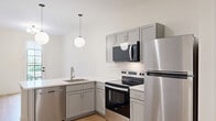 Located at 700 E. Long St. in Columbus, Ohio, this efficiently designed one-bedroom, one-bathroom unit offers a clean, modern aesthetic throughout. Light hardwood flooring runs continuously across the entire space, creating a cohesive and airy feel.

The open-concept kitchen and dining area serves as the heart of the unit. The kitchen features gray cabinetry, white subway tile backsplash, a sleek white quartz peninsula with an undermount sink, and stainless steel appliances including a refrigerator, electric range, and microwave. Globe pendant lights hang above the peninsula, adding a contemporary touch. A glass-paned exterior door floods the dining area with natural light and provides views of the surrounding neighborhood.

The bedroom is a well-proportioned, quiet retreat with crisp white walls and includes access to a dedicated walk-in closet outfitted with built-in shelving and a full-length hanging rod—offering generous organization options.

The bathroom is finished with a warm wood vanity topped with a white countertop, an illuminated mirror, and light hardwood-style flooring that maintains the unit's consistent design language. The clean white walls and minimalist fixtures complete the modern look.

Throughout, the unit maintains a bright, neutral palette that maximizes the sense of openness and provides a versatile canvas for personalization.