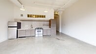 Located at 675 Ponce de Leon Ave NE in Atlanta's vibrant Ponce City Market corridor, this two-bedroom, one-bathroom unit showcases the character of an industrial loft conversion. Polished concrete floors run throughout, complementing the raw, urban aesthetic of the space.

The main living area is anchored by a striking wall of original exposed brick fitted with large, multi-pane factory-style windows that flood the room with natural light and offer views of the surrounding cityscape. The open-concept kitchen features modern flat-panel cabinetry in a warm wood-tone finish, subway tile backsplash, a gas range, and pendant lighting suspended from high ceilings with visible ductwork — a hallmark of the building's industrial heritage.

A long, light-filled hallway connects the living areas to the two bedrooms. The primary bedroom is generously sized, offering transom windows that borrow light from adjacent spaces. The second bedroom is a comfortable, well-proportioned room with concrete floors and clean white walls. Both rooms feature panel-style doors with crisp white millwork.

The bathroom is thoughtfully designed with large-format gray tile flooring, a wood-grain floating vanity, an undermount sink, built-in shelving, and a full mirror — offering a clean, modern finish that contrasts the loft's industrial character throughout.
