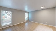 This single-floor unit offers a clean, modern aesthetic defined by neutral gray walls, white trim, and textured ceilings throughout. The layout includes multiple distinct living areas, with hard surface flooring—light wood-look planks—featured in the main living spaces and kitchen, while plush carpet covers the bedroom areas for added comfort.

The spacious main living area benefits from multiple windows fitted with horizontal blinds, allowing ample natural light to fill the room. A secondary living or flex space also features hardwood-style flooring and additional windows with outdoor views. Both areas provide generous open space suitable for a variety of furniture arrangements.

The kitchen is efficiently designed with gray cabinetry, white countertops, a double stainless steel sink, and a classic white subway tile backsplash. Stainless steel appliances, including a refrigerator, microwave, and electric range, complete the functional cooking space.

The carpeted bedroom includes access to a walk-in closet, a window for natural light, and an en-suite bathroom featuring a vanity and toilet. An additional carpeted room with a connected bathroom provides flexible use as a second bedroom or office. The thoughtful layout and consistent finishes throughout give the space a cohesive, move-in-ready appeal.