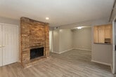 Located at 5208 11th St in Lubbock, Texas, this single-story home offers a well-organized layout designed for comfortable everyday living. The living area is anchored by a striking floor-to-ceiling brick fireplace, adding warmth and character to the space. Light wood-look flooring runs consistently throughout the home, complementing the neutral gray wall tones and crisp white trim for a clean, cohesive aesthetic. The living room opens into an adjacent flex or dining space and connects seamlessly to the kitchen, which features white cabinetry, gray laminate countertops, a double-basin sink, and a white range with overhead ventilation. A sliding glass door in the living area provides direct access to an outdoor patio and fills the interior with natural light. The bedrooms are comfortably sized, each with wood-look flooring, windows with blinds, ceiling fixtures, and closet access. The bathrooms are finished with gray countertops, white cabinetry, oval mirrors, and light, neutral tiling. One bathroom features an extended vanity with ample cabinet storage. Throughout the home, the textured ceilings, consistent finishes, and neutral palette create a bright and practical living environment well-suited to a variety of lifestyles.