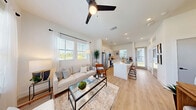 Located at 2611 E Braker Ln in Austin, TX, this single-story, one-bedroom, one-bathroom home offers a clean, modern aesthetic throughout its well-organized floor plan. Light wood-style flooring and crisp white walls create a bright, cohesive ambiance from room to room.

The open-concept living area welcomes abundant natural light through large double-hung windows dressed with sheer curtains and wood blinds, offering views of the surrounding neighborhood. The space flows naturally into the kitchen, which is outfitted with white shaker cabinets, black hardware accents, quartz countertops, a subway tile backsplash, stainless steel appliances, and a central island — ideal for both cooking and casual dining. Elevated ceilings in the kitchen area add an airy, spacious feel.

The bedroom is a comfortable retreat featuring plush carpet flooring, oversized windows with neighborhood views, and direct access to both a closet and the bathroom. The bathroom showcases a dual-sink vanity with white cabinetry, matte black fixtures, framed mirrors, and a full tub-shower combination with white subway tile surround.

Outside, a covered patio with a wood post and black metal railing fence offers a private green space. The home's board-and-batten exterior complements the modern farmhouse character of the surrounding community.