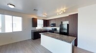 This single-floor residence offers a thoughtfully designed living space anchored by a standout kitchen. The kitchen is outfitted with rich, dark espresso-toned cabinetry that extends floor to ceiling, providing generous storage throughout. Granite countertops in warm earth tones add a polished, durable work surface, and the central kitchen island offers additional prep and gathering space. Black appliances — including a gas range, refrigerator, and dishwasher — complement the dark cabinetry for a cohesive, contemporary aesthetic. Track lighting and recessed fixtures illuminate the space efficiently, while multiple windows invite natural light to brighten the interior. The light hardwood-style flooring runs seamlessly throughout, creating a clean and modern foundation that ties the space together. The layout is open and functional, with the kitchen flowing naturally into the surrounding living areas. The overall ambiance is modern and practical, with quality finishes that balance style and everyday usability. This residence provides a comfortable, well-equipped environment suited for a variety of lifestyles.