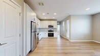 Located at 1107 W Exposition Ave in Denver, CO, this well-appointed 2-bedroom, 1-bathroom home offers a thoughtfully designed single-floor layout with a clean, modern aesthetic throughout. Light wood-tone flooring flows through the open-concept living and kitchen areas, creating a bright and cohesive atmosphere. The kitchen is equipped with stainless steel appliances—including a refrigerator, range, microwave, and dishwasher—complemented by white shaker cabinetry, granite countertops, and recessed lighting. The living area connects seamlessly to a private balcony, adding an outdoor retreat to the space. In-unit stacked laundry is conveniently tucked within its own dedicated area. Both bedrooms feature plush carpeting, generous closet space, and windows that invite natural light; the second bedroom includes corner windows with neighborhood views. The primary bedroom provides direct access to the full bathroom, which boasts a dual-sink vanity with granite countertops, white cabinetry with matte black hardware, a large mirror, and tiled walls. Four closets throughout the unit—including a spacious walk-in—ensure ample storage. Neutral wall tones and consistent finishes lend the entire home a polished, move-in-ready feel.