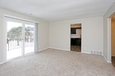 This single-floor residence offers a functional and cohesive layout across its key living spaces. The kitchen is a standout feature, showcasing dark espresso cabinetry paired with light granite countertops, a classic white subway tile backsplash, and wood-look flooring. Black appliances, including a range, built-in microwave, dishwasher, and refrigerator, complete the space, with a louvered pantry door providing additional storage.

The living area is generously sized, finished with neutral carpet and a textured ceiling, and connects seamlessly to the kitchen and a hallway leading to the remaining rooms. A sliding glass door floods the space with natural light and opens to a balcony with outdoor views. A bay window in the bedroom similarly enhances the sense of brightness and openness.

The bedroom features plush carpet, neutral wall tones, and access to a spacious walk-in closet equipped with double hanging rods. The bathroom includes a tub and shower combination with a window above for natural light, wood-look tile flooring, and clean white fixtures. A dedicated entry hallway with a utility access panel provides a practical transition into the main living spaces.