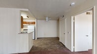 This 2-bedroom, 1-bathroom unit is thoughtfully laid out across a single floor, making efficient use of its compact footprint. The living area features wood-look flooring and a ceiling fan, creating a comfortable and practical space. It flows seamlessly into the kitchen, which is equipped with warm wood cabinetry, light countertops, a full suite of appliances including a refrigerator, electric range, and dishwasher, and durable wood-look tile flooring — all set within a U-shaped layout that maximizes workspace.

A sliding glass door in the living area opens to an outdoor balcony, allowing natural light to pour in and providing a pleasant view of surrounding greenery. Vertical blinds offer privacy and light control throughout.

Both bedrooms are carpeted and bright, each featuring windows with vertical blinds that let in natural light. The primary bedroom includes mirrored sliding closet doors and an adjacent secondary closet or utility space. The second bedroom is cozy with its own window and a view of outdoor foliage.

The single bathroom features a wood-vanity with a single-basin sink, a large mirror, and a combined tub and shower. The textured ceilings are consistent throughout the unit, adding a classic residential character to the overall space.