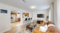 Located at 1335 Dreibelbis St in State College, PA, this two-story home offers 3 bedrooms and 4 bathrooms across two well-designed floors. The main level welcomes you through a dedicated entrance that opens into a bright, open-concept living and kitchen area. The living room features light hardwood-style flooring, large windows dressed with sheer curtains that fill the space with natural light, and a wall-mounted TV. A breakfast bar with sleek black stools connects seamlessly to the kitchen, which is outfitted with warm wood cabinetry, stainless steel appliances including a refrigerator, dishwasher, microwave, and range, plus tile flooring and ample counter space. A laundry area and multiple closets add everyday convenience on this floor. The upper level hosts all three bedrooms, including a generously sized primary bedroom with carpeted flooring and a bright window with outdoor views. The additional bedrooms are equally well-appointed, each with natural light, carpet, and open closet storage. Four clean, tile-floored bathrooms with wood vanities are distributed throughout both floors to ensure comfort and privacy. A staircase connects the two levels, completing this functional and well-laid-out home.