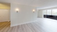 This single-floor unit offers a thoughtfully designed layout with a clean, modern aesthetic throughout. The open living and dining areas are finished with light-toned hardwood-style flooring and neutral walls, creating a bright and cohesive atmosphere. Wall sconces and a chandelier provide warm accent lighting, complementing the textured ceiling panels overhead. Windows allow natural light to filter in, enhancing the spacious feel of these connected areas.

The galley-style kitchen is well-equipped with stainless steel appliances, including a refrigerator, electric range, and microwave. Gray shaker-style cabinetry lines both walls, paired with light quartz countertops and a classic subway tile backsplash, offering ample storage and prep space. Light hardwood-style flooring continues seamlessly through this area.

The bedrooms feature plush neutral carpet and generous closet space with built-in hanging rods. Each room maintains the unit's soft, neutral color palette and benefits from natural light through blinded windows.

The bathrooms are finished with gray shaker vanities topped with speckled quartz countertops, undermount sinks, and illuminated mirrors. Each includes a full tub-shower combination with white tile surround, chrome fixtures, and classic white floor tile, delivering a clean and functional design.