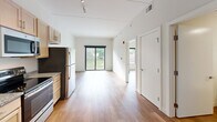 Located at 1359 Plainfield Ave NE in Grand Rapids, Michigan, this one-bedroom, one-bathroom unit offers a well-designed layout that maximizes every inch of its compact footprint. The open living area flows seamlessly from the kitchen, creating a bright, airy atmosphere enhanced by hardwood-style flooring throughout and crisp white walls that reflect natural light.

The kitchen is a standout feature, outfitted with a full suite of stainless steel appliances — including a refrigerator, electric range, built-in microwave, and dishwasher — complemented by light maple cabinetry, granite-style countertops, and a single-basin sink. Track lighting overhead adds both function and a modern touch. The kitchen opens directly into the living area, which benefits from large sliding glass doors leading to a private balcony with pleasant outdoor views of the surrounding neighborhood.

The bedroom is a calm, private retreat with a large window that frames leafy street views and fills the room with natural light. The hardwood-style flooring continues here, maintaining a cohesive aesthetic throughout the unit. The bathroom is clean and functional, with a straightforward design. This unit is an excellent option for those seeking a modern, low-maintenance space in a convenient Grand Rapids location.