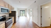 Located at 1359 Plainfield Ave NE in Grand Rapids, Michigan, this one-bedroom, one-bathroom unit offers a well-designed layout that maximizes every inch of its compact footprint. The open living area flows seamlessly from the kitchen, creating a bright, airy atmosphere enhanced by hardwood-style flooring throughout and crisp white walls that reflect natural light.

The kitchen is a standout feature, outfitted with a full suite of stainless steel appliances — including a refrigerator, electric range, built-in microwave, and dishwasher — complemented by light maple cabinetry, granite-style countertops, and a single-basin sink. Track lighting overhead adds both function and a modern touch. The kitchen opens directly into the living area, which benefits from large sliding glass doors leading to a private balcony with pleasant outdoor views of the surrounding neighborhood.

The bedroom is a calm, private retreat with a large window that frames leafy street views and fills the room with natural light. The hardwood-style flooring continues here, maintaining a cohesive aesthetic throughout the unit. The bathroom is clean and functional, with a straightforward design. This unit is an excellent option for those seeking a modern, low-maintenance space in a convenient Grand Rapids location.