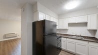 Located at 393 Lockheed Ave SE in Marietta, Georgia, this efficiently designed single-floor unit makes smart use of its intimate footprint. The open-concept kitchen and living area serves as the heart of the space, featuring warm wood-look vinyl flooring that flows throughout. The kitchen stands out with crisp white shaker-style cabinetry extending to the ceiling for maximum storage, dark granite-look countertops, a classic white subway tile backsplash, and black appliances including a full-size refrigerator and range. A dedicated living area benefits from a ceiling fan with light fixture and a window dressed with blinds that allows natural light to filter in. A separate room offers dual closets side by side, providing generous storage, and is also fitted with a ceiling fan. The bathroom includes a full soaking tub with an overhead shower, chrome fixtures, and a wall-mounted mirror above the sink, all finished in a clean, neutral palette. Textured ceilings and crisp white trim are consistent throughout the unit, lending a cohesive and tidy aesthetic. A wall-mounted HVAC unit ensures year-round comfort.
