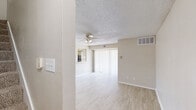 Located at 15550 Knoll Trail Dr in Dallas, TX, this two-story residence offers 2 bedrooms and 3 bathrooms across two thoughtfully distributed floors. The main level features an open living room with light-toned wood-style flooring, a ceiling fan, and a textured ceiling. Large sliding doors invite natural light and lead to the exterior, while a pass-through connects the living area to the galley-style kitchen. The kitchen is equipped with black appliances, white cabinetry, light countertops, and a window at the far end that brings in additional natural light. A full bathroom on this level features a single-sink vanity with white cabinetry and a tub-shower combination. The upper floor houses both bedrooms, each finished with plush carpeting, ceiling fans, and textured ceilings. The primary bedroom is generously sized and includes mirrored sliding closet doors with gold-tone frames. The second bedroom features a built-in shelving closet system and dual windows overlooking the outdoors. Both bedrooms are served by well-appointed bathrooms. Neutral warm-beige tones carry throughout the home, creating a cohesive and inviting atmosphere well-suited to a variety of interior styles.