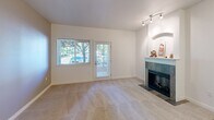 Located at 5212 88th Street Ct SW in Lakewood, Washington, this ground-floor unit offers a thoughtfully designed single-level layout. The living room serves as the heart of the space, featuring plush carpet flooring, a tile-surround fireplace with a classic mantel, and a combination of a window and a private patio door that fills the room with natural light and provides direct outdoor access. Track lighting accents the arched niche beside the fireplace, adding a decorative architectural detail.

The kitchen is well-equipped with rich dark-wood cabinetry, granite countertops, and a full suite of stainless steel appliances including a refrigerator, range, and built-in microwave. A breakfast bar-style counter connects the kitchen to the living area, creating an open, functional flow. Tile flooring runs throughout the kitchen.

The bedroom is generously sized, featuring two windows that frame views of surrounding greenery, soft carpet underfoot, and dual closets providing ample storage. The bathroom includes a full tub-shower combination with a curtain rod and tile flooring, maintaining a clean, functional aesthetic throughout. Neutral tones unify the entire space.