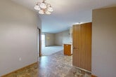 This single-floor, 2-bedroom, 1-bathroom unit offers a practical and comfortable layout designed for everyday living. The entryway, finished with durable stone-look tile flooring, opens into a combined kitchen and living area. The kitchen features warm oak cabinetry, ample counter space, a peninsula with a built-in sink, and a full suite of appliances including an electric range and refrigerator. A dedicated pantry closet adjacent to the kitchen provides generous shelving for storage. A multi-bulb chandelier in the entry adds a welcoming focal point overhead. The living area is carpeted and bathed in natural light, leading directly to a private balcony through a sliding glass door — offering outdoor access and views. Both bedrooms are carpeted and neutrally finished, with the primary bedroom featuring a spacious closet. The full bathroom includes a single-sink vanity with oak cabinetry, a large mirror, a soaking tub, and stone-look tile floors consistent with the rest of the unit. Throughout the space, four closets provide exceptional storage capacity. Neutral wall tones, wood trim accents, and baseboard heating complete the clean, functional aesthetic of this thoughtfully organized home.