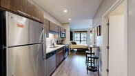 Located at 1400 Walnut St in the heart of Des Moines, Iowa, this efficiently designed one-bedroom, one-bathroom unit offers a thoughtfully organized single-floor layout. The open-concept interior connects the kitchen and living area seamlessly, maximizing the use of space throughout.

The kitchen is outfitted with dark walnut cabinetry, white subway tile backsplash, light countertops, and a full suite of stainless steel appliances including a refrigerator, range, microwave, and dishwasher. Wood-look plank flooring runs throughout the main living area, adding warmth to the contemporary aesthetic.

The bedroom features a built-in Murphy-style bed framed by rich wood paneling and flanked by open shelving units, offering smart storage solutions without sacrificing style. Large windows with roller shades allow natural light to fill the room while providing views of the surrounding urban cityscape.

The bathroom includes a full soaking tub and shower combination with white tile surround, complemented by neutral-toned walls and wood-look flooring. A dedicated closet provides additional storage.

Recessed lighting throughout and a clean, neutral color palette create a cohesive and modern ambiance, making this unit a functional and stylish urban residence in downtown Des Moines.