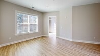 Located at 235 Hollis Rd in Charlotte, NC, this well-appointed one-bedroom, two-bathroom unit offers an efficient and thoughtfully designed single-level layout. The open-concept kitchen and living area is anchored by a fully equipped kitchen featuring taupe shaker-style cabinetry with matte black hardware, dark quartz countertops, a textured subway tile backsplash, stainless steel appliances including a French door refrigerator, electric range, microwave, and dishwasher. Light hardwood-style flooring runs throughout the main living areas, complementing the neutral warm-gray walls and creating a bright, cohesive aesthetic. The living room benefits from large windows that invite natural light and offer views of the surrounding area. The primary bedroom is a comfortable, carpeted retreat with a window providing additional natural light. Two bathrooms serve the unit — one features white shaker cabinetry, dark quartz countertops, matte black fixtures, and marble-style tile flooring, while the second showcases a stunning floor-to-ceiling marble-look tiled walk-in shower with a built-in bench and glass enclosure. A walk-in closet adds practical storage to complete this clean, modern residence.