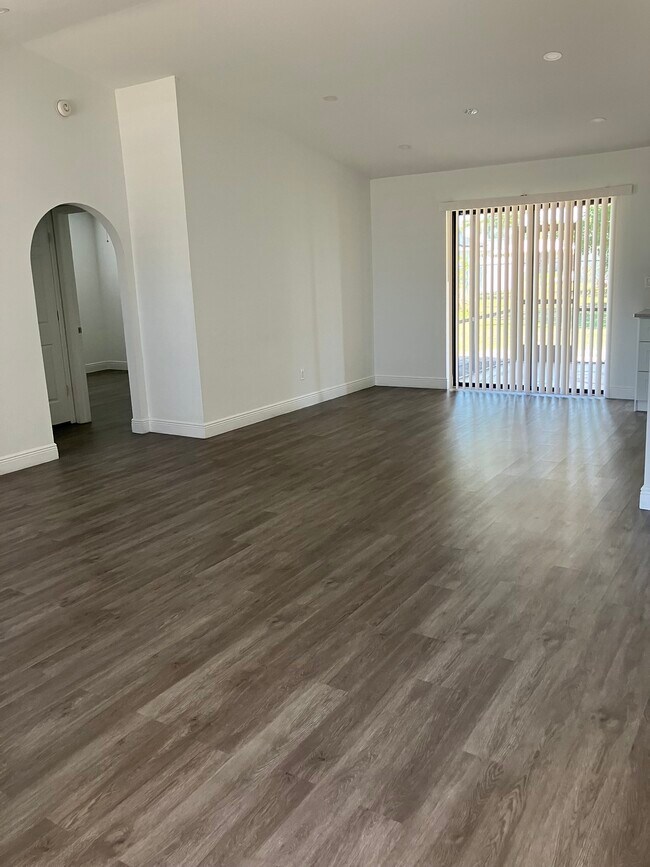 View of living and dining area from front entry. Sliding door leads to screeened lanai. - 3231 SW 1st Pl