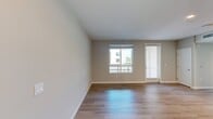 This 610-square-foot, one-bedroom, one-bathroom apartment at North Grove (Unit A1D, 15-202) in Riverside, CA delivers a clean, modern aesthetic throughout its thoughtfully designed single-floor layout. The open-concept kitchen is a standout feature, boasting two-tone cabinetry with flat-panel upper cabinets in light gray and warm wood-toned lower cabinets, a marble-style tile backsplash, quartz countertops, and a full suite of stainless steel appliances including a refrigerator, range, microwave, and dishwasher. Light hardwood flooring runs through the kitchen and living areas, enhancing the bright, airy feel of the space. The 160-square-foot primary bedroom is finished with plush carpet and features large windows that invite abundant natural light and views of the surrounding community and greenery. The bathroom offers hardwood-style flooring, a wood-toned vanity with a wide mirror, and a full tub-shower combination. A connecting hallway links the living spaces efficiently. Recessed lighting throughout adds a polished, contemporary touch. The unit also provides access to a balcony overlooking a covered parking area with views of the modern residential complex and mature trees beyond.