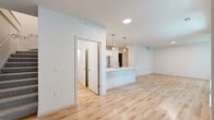 Located at 2152 Middleton Beach Rd in Middleton, Wisconsin, this contemporary two-story property offers 3 bedrooms and 3 bathrooms across a generously sized floor plan. The main level comprises the majority of the living space and is anchored by an open-concept kitchen and living area. The kitchen is outfitted with sleek white cabinetry, stainless steel appliances, a large center island with a white quartz countertop, and stylish pendant lighting — all set atop warm light wood flooring that flows throughout the main level. Large windows are featured throughout the home, inviting abundant natural light and offering pleasant views of the lush, tree-lined surroundings outside. The bedrooms vary in finish, with some featuring soft carpeting and others continuing the light hardwood flooring. Closets include a well-appointed walk-in with built-in shelving and hanging rods. The bathrooms are finished in crisp white tones with wood-look flooring and walk-in shower enclosures. The upper floor provides additional bedroom space. A spacious underground parking garage with marked stalls and dedicated bicycle storage rounds out this property's practical amenities. The exterior features modern horizontal siding and manicured green lawns.