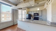 This two-story loft-style residence in Memphis, TN offers a compelling blend of industrial character and contemporary upgrades. Exposed concrete beams, raw brick accents, and visible ductwork on the ceilings lend an authentic urban aesthetic throughout, while warm hardwood-style flooring grounds each room with a cohesive, modern feel.

The open-concept kitchen serves as a central hub, featuring a large granite-topped peninsula with an undermount sink, gray cabinetry, a patterned tile backsplash, and black appliances including a refrigerator, range, and over-the-range microwave. Pendant lighting and natural light from nearby windows complete the space.

Each of the three bedrooms offers a comfortable layout with hardwood-style flooring and exposed structural ceiling elements that reinforce the loft character. Select bedrooms include walk-in closets for added storage.

All three bathrooms are finished with striking marble-veined tile in the showers and tub surrounds, paired with granite-topped vanities and hardwood-style flooring. Both walk-in glass showers and a tub/shower combination are represented across the bathrooms.

A dedicated laundry room with a full-size washer and dryer adds everyday convenience. The two-floor layout provides separation and versatility, making this Memphis residence a distinctive urban retreat.