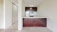 Located at 810 Thornton Street Southeast in Minneapolis, MN, this one-bedroom, one-bathroom unit offers a well-organized single-floor layout with a bright, open feel throughout. The living room is a standout space, anchored by expansive floor-to-ceiling windows that frame lush treetop views alongside a striking Minneapolis skyline backdrop, flooding the room with natural light and plush carpet underfoot. The kitchen features a practical galley-style configuration with dark espresso cabinetry, white appliances including an electric range and dishwasher, light countertops, and clean tile flooring. A peninsula counter opens the kitchen toward the living area, creating a connected and functional flow. The spacious primary bedroom is carpeted and includes a full wall of louvered bifold closet doors, providing substantial storage. In total, the unit offers three closets, ensuring ample organization throughout. The full bathroom is finished with mosaic tile flooring, a tiled shower-tub combo, a white vanity with under-cabinet storage, and a well-lit mirror above the sink. A hallway connects the rooms efficiently, maintaining a logical and comfortable layout. This unit combines practical design with notable views in a sought-after Minneapolis location near the University of Minnesota.