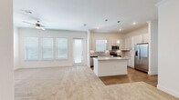 Located at 3030 Greenbusch Rd in Katy, TX, this single-story, 3-bedroom, 2-bathroom home offers a well-designed open-concept floor plan with a bright, neutral color palette throughout. The heart of the home is the kitchen, which features light wood cabinetry, granite countertops, a large center island with pendant lighting, a full suite of stainless steel appliances, a tile backsplash, and hardwood-style flooring. The kitchen flows seamlessly into the living area, which is carpeted and filled with natural light from multiple windows and a glass door leading outside. A ceiling fan adds comfort to the living space. The primary bedroom is a generous size and connects to an en-suite bathroom boasting dual granite-topped sinks, a large mirror, and hardwood-style flooring, with laundry access nearby. The second bathroom features bold dark tile surround on a soaking tub/shower combo, a granite vanity, and hardwood-style flooring. The two additional bedrooms are carpeted and receive natural light through window blinds. Two closets provide ample storage, including a walk-in with built-in shelving and hanging rods. The open layout and consistent finishes give the home a cohesive, modern feel.