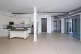 Located at 710 N El Centro Ave in the heart of Hollywood, Los Angeles, this contemporary single-floor unit showcases a clean, modern aesthetic throughout. The open-concept living area is defined by light hardwood flooring, crisp white walls, and striking exposed silver ductwork that runs along the ceiling, lending an industrial-chic character to the space. Large floor-to-ceiling sliding glass doors flood the living area with abundant natural light and open directly onto a private balcony, offering views of swaying palm trees and the surrounding neighborhood streetscape.

The kitchen is well-appointed with sleek white cabinetry extending to the ceiling, dark charcoal countertops, a classic white subway tile backsplash, and a full suite of stainless steel appliances including a gas range, over-the-range microwave, and a French door refrigerator. A central island provides additional prep and dining space, making the kitchen as functional as it is stylish.

The bedroom area features a walk-in closet with ample hanging and storage space, while the bathroom impresses with a frameless glass-enclosed walk-in shower clad in large-format marble-look tile with mosaic tile flooring. A secondary room with its own window offers flexibility as a bedroom or home office. Rail lighting and thoughtful finishes complete this polished Hollywood residence.