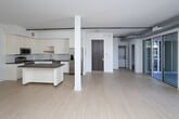 Located at 710 N El Centro Ave in the heart of Hollywood, Los Angeles, this contemporary single-floor unit showcases a clean, modern aesthetic throughout. The open-concept living area is defined by light hardwood flooring, crisp white walls, and striking exposed silver ductwork that runs along the ceiling, lending an industrial-chic character to the space. Large floor-to-ceiling sliding glass doors flood the living area with abundant natural light and open directly onto a private balcony, offering views of swaying palm trees and the surrounding neighborhood streetscape.

The kitchen is well-appointed with sleek white cabinetry extending to the ceiling, dark charcoal countertops, a classic white subway tile backsplash, and a full suite of stainless steel appliances including a gas range, over-the-range microwave, and a French door refrigerator. A central island provides additional prep and dining space, making the kitchen as functional as it is stylish.

The bedroom area features a walk-in closet with ample hanging and storage space, while the bathroom impresses with a frameless glass-enclosed walk-in shower clad in large-format marble-look tile with mosaic tile flooring. A secondary room with its own window offers flexibility as a bedroom or home office. Rail lighting and thoughtful finishes complete this polished Hollywood residence.