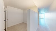 Located at 45 Lansing Street in San Francisco's SoMa district, this modern studio offers a thoughtfully designed single-floor layout comprising an open living area, kitchen, bathroom, and hallway. Light wood-toned flooring runs throughout, complementing the crisp white walls and lending a clean, contemporary aesthetic to the entire space.

The living area is defined by expansive floor-to-ceiling sliding glass doors that open to a balcony, framing sweeping views of the San Francisco skyline and the Bay Bridge. Natural light pours in generously, enhancing the open and airy feel of the space.

The kitchen is outfitted with high-gloss white cabinetry extending to the ceiling for ample storage, a dark countertop, stainless steel appliances including a built-in oven and refrigerator, and a single-basin sink — all arranged in a streamlined galley configuration that maximizes functionality.

The bathroom features large-format neutral floor tiles, elegant marble-style wall surrounds encasing a full soaking tub, a wall-mounted vanity mirror, and recessed linear lighting that creates a clean and polished finish. A hallway connects the rooms and provides a clear sense of flow throughout the layout. Overall, the space presents a minimalist, modern character well-suited to urban living in downtown San Francisco.